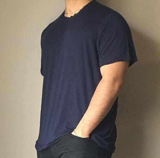 man shoulders in pockets wearing navy blue tshirt